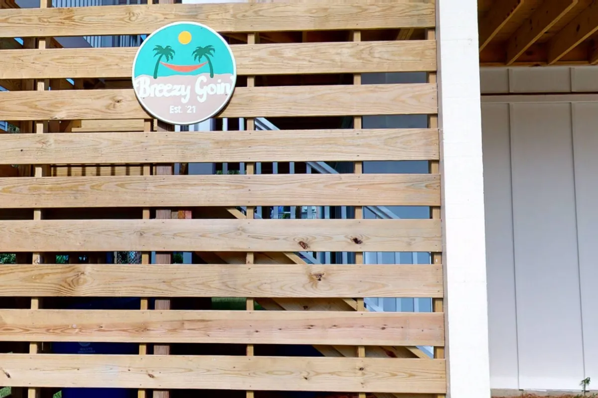 The exterior of Breezy Goin, with a prominent wooden slatted wall and the welcoming Breezy Goin sign. The entrance is inviting, blending modern style with a laid-back, residential vibe. This image sets the tone for arrival and establishes the environment as one tailored for guests seeking both productivity and relaxation.