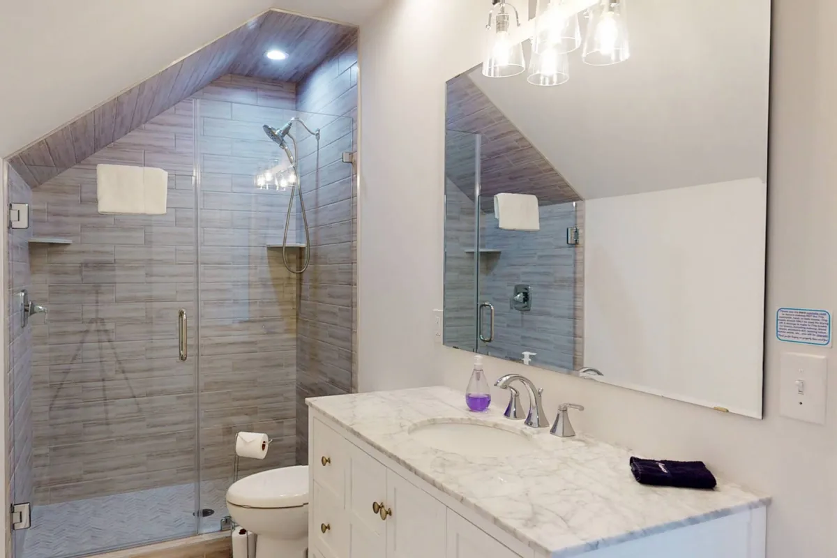 A luxurious bathroom with a spacious glass shower enclosure, a sleek marble countertop, and a mirrored vanity. The design and fresh towels exude a spa-like, refreshing ambiance.